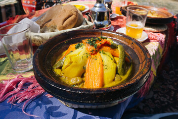 Berber Moroccan tagine dish. Hot lunch served. Traditional food plate. Colorful table setting. Spiced vegetables aroma. Cultural outdoor dining. Local taste moment. Authentic north africa cuisine. © Paweł Michałowski