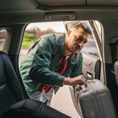 Adult man pack and loading luggage baggage into car