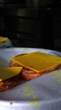 Melty cheese smash burger patty gently set on a toasted bun, showcasing texture and steam &ndash; cinematic burger preparation shot