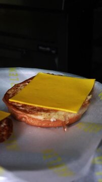Close-up of a juicy cheese smash burger being placed on a soft bun on a hot griddle &ndash; high-quality slow motion food footage