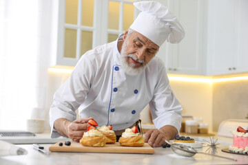 Elderly pastry chef making desserts at table in kitchen