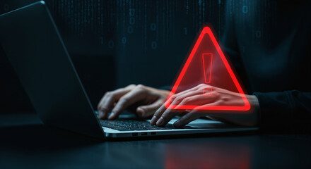 A hooded figure typing on a laptop with a warning triangle overlay, illustrating hacking, online threat, and cybersecurity vulnerability in a technological context