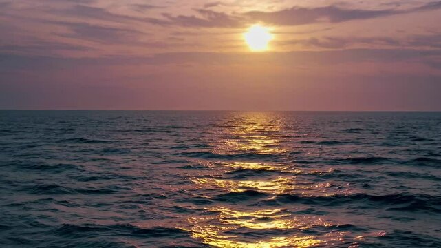 Tranquil sunset over ocean waves with golden reflections under cloudy sky