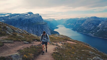 Fototapeta premium A person climbing a challenging mountain path with a serene lake visible in the distance