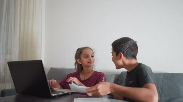 boy proudly shows his handwritten work to friend who smiles while reviewing it then playfully slaps his head making him shake his head with mild frustration in funny supportive sibling