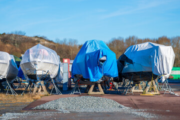 stored boats wrapped in protective tarps at dockyard.
