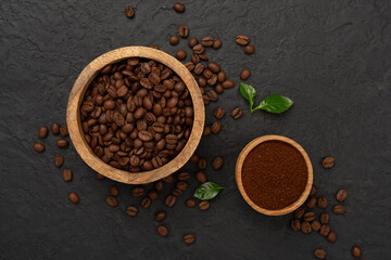 Roasted coffee beans with leaves on concrete background,top view