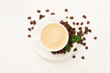 Cup of coffee with coffee beans and leaves on concrete background,top view