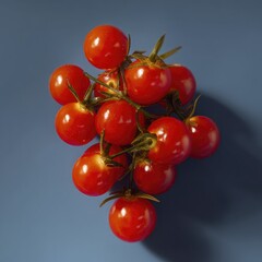 Bright red cherry tomatoes on their stalks arranged against a contrasting blue surface for striking visual impact.