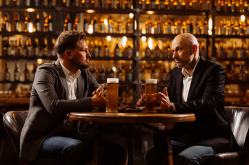 Two Men Engaged in Deep Conversation Over Beer in a Cozy Bar Setting