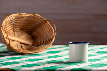 straw basket and cup, an empty straw basket and a coffee cup on a rustic table with a green and...