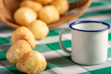 Brazilian cheese bread, delicious Brazilian cheese bread and accessories on a rustic table with a green and white checkered tablecloth, selective focus.