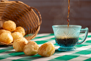 Brazilian cheese bread with coffee, delicious Brazilian cheese bread with a cup of coffee and accessories on a rustic table with a green and white checkered tablecloth, selective focus.