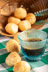 Brazilian cheese bread with coffee, delicious Brazilian cheese bread with a cup of coffee and accessories on a rustic table with a green and white checkered tablecloth, selective focus.