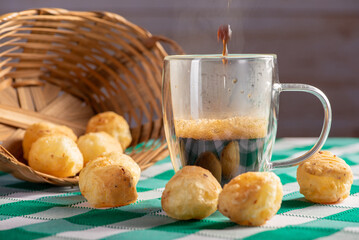 Brazilian cheese bread with coffee, delicious Brazilian cheese bread with a cup of coffee and accessories on a rustic table with a green and white checkered tablecloth, selective focus.