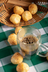Brazilian cheese bread with coffee, delicious Brazilian cheese bread with a cup of coffee and accessories on a rustic table with a green and white checkered tablecloth, selective focus.