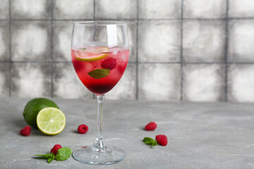 Glass of fresh raspberry mojito on grey table