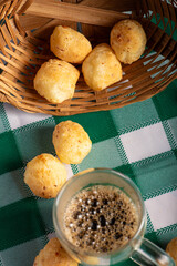 Brazilian cheese bread with coffee, delicious Brazilian cheese bread with a cup of coffee and accessories on a rustic table with a green and white checkered tablecloth, selective focus.
