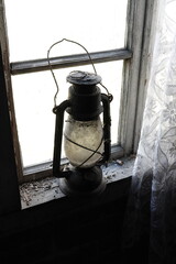 Lampa naftowa widoczna na tle starego okna  © tomo81