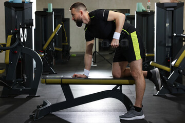 Athletic man training with dumbbell in gym
