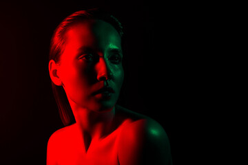 Dramatic portrait of a young woman highlighted in creative red and green neon lighting against a dark background