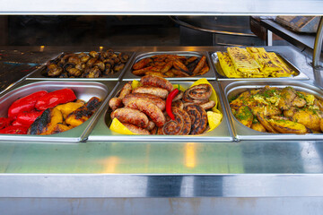 Street food. Large food display with vegetables and grilled meat barbecue in an open-air amusement park (close-up)