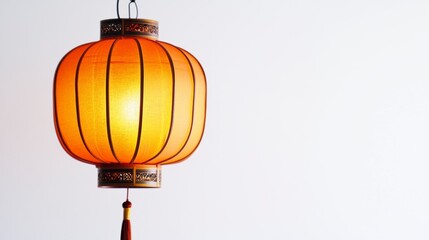 Obraz premium Glowing orange silk Chinese lantern hanging against a white background.