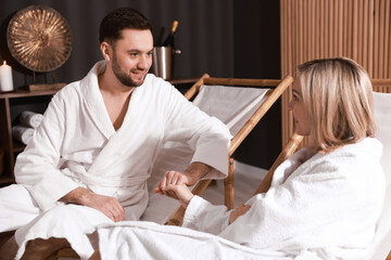 Obraz premium Happy couple in bathrobes relaxing in spa salon