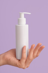 Female hand with bottle of natural cream on lilac background, closeup