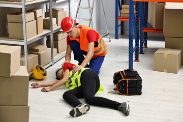 Accident at work. Man helping his unconscious colleague in warehouse