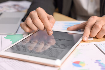 Electronic signature. Man using tablet at table, closeup