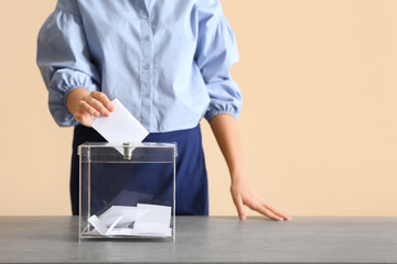 Voting young woman near ballot box on table at polling station, closeup