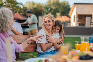 Happy family enjoying backyard barbecue, mother hugging daughter