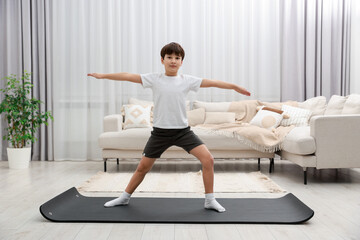 Fototapeta premium Boy doing exercise on fitness mat at home. Sport activity