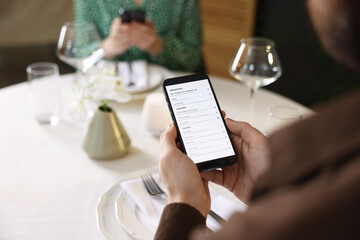 Couple choosing dishes from digital menu at restaurant, closeup