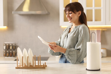 Woman wiping plate with paper towel at white marble table in kitchen