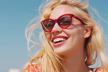 Happy blonde woman wearing sunglasses and smiling under blue sky