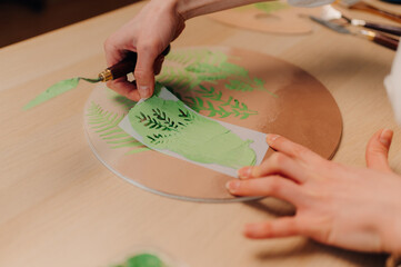 Artist using stencil and green paint on ceramics for decoration
