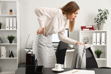 Young businesswoman suffering from back pain in office