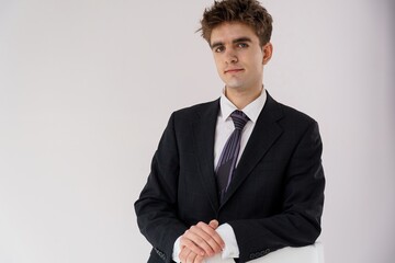 Portrait of a young businessman in a dark suit and purple tie, looking confidently at the camera against a plain white background. He has short brown hair and fair skin