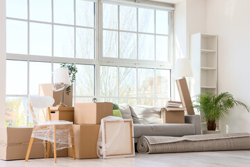 Furniture, houseplants and cardboard boxes with belongings in new apartment. Moving house concept