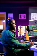 Skilled composer writing rhymes and lyrics to create new music in home studio, thinking about harmonic notes and verses to compose cool songs. Songwriter producing soundtracks with gear.