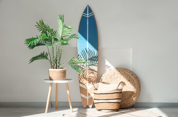 Interior of modern stylish room with surfboard and houseplant near white wall