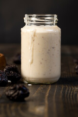 milk yogurt with prune flavor with dried plum slices, glass jar with natural prune yogurt, side view
