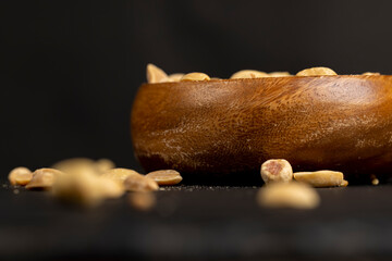 fried peanut in a wooden bowl, fried yellow peanuts with a little salt on the table