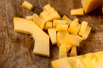 orange pumpkin cut into pieces of different sizes, preparing the pumpkin for cooking by cutting...