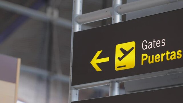 Airport gate direction sign with bilingual English-Spanish text