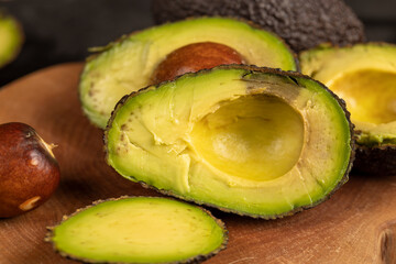 sliced small avocado with soft overripe flesh on a wooden board