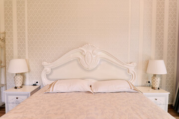 White wooden double bed with carved high back and bedside tables