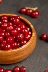 ripe currant berries poured in a wooden bowl, harvest small red currant berries on the kitchen table in a bowl, closeup